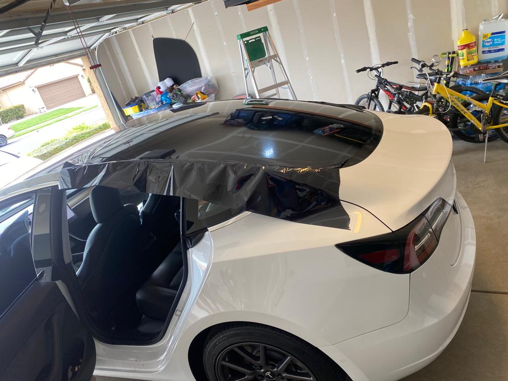 White Tesla Model 3 with window film being installed on the glass roof