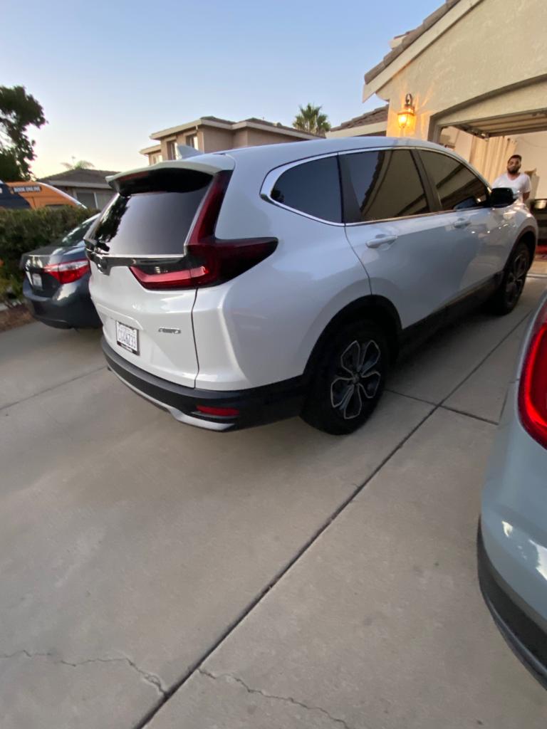 White Honda CR-V with dark tinted windows on a residential driveway