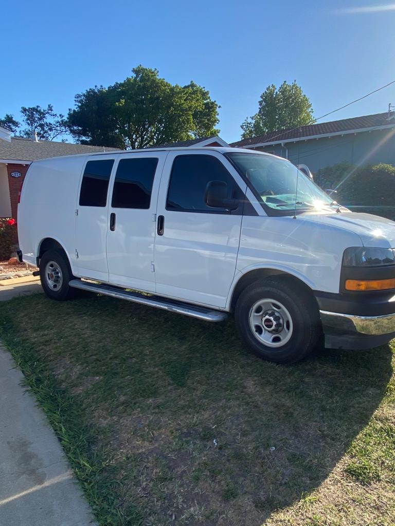 White GMC Savana cargo van with tinted windows parked at a home