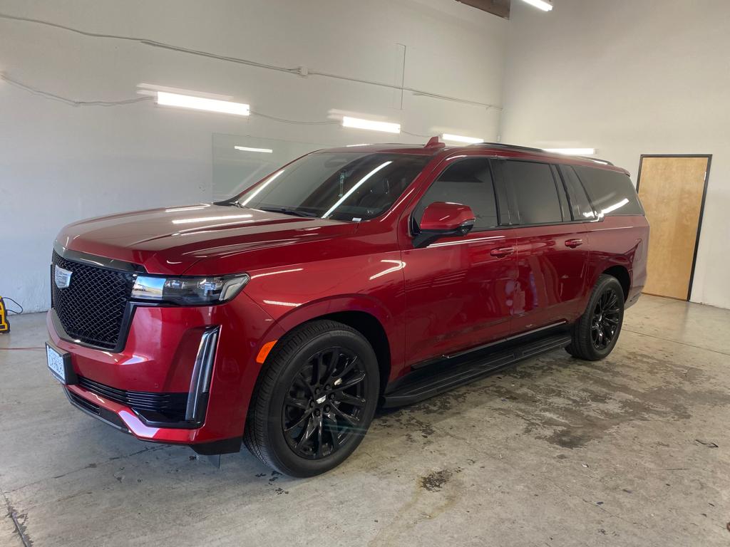 Red Cadillac Escalade ESV with dark tinted windows in a garage