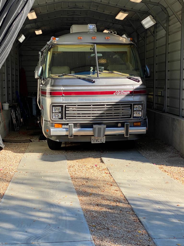Airstream motorhome with tinted cab and coach glass under a covered carport